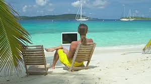 woman at beach working on laptop